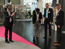 Träger der Brille konnten eine 3D Simulation einer Langhammer Palettieranlage entweder verkleinert auf dem Tresen, oder in Originalgröße auf dem Messestand sehen. Bild: Applied Information Technologies GmbH & Co. KG